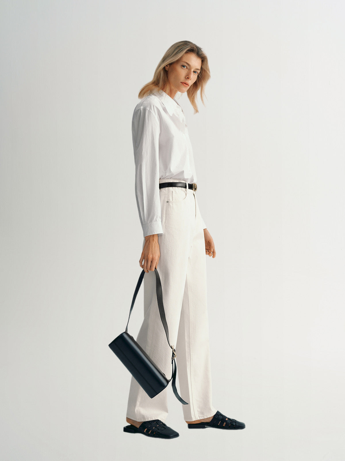 Model wearing a stylish pure cotton shirt with classic collar, paired with light trousers and a black bag.