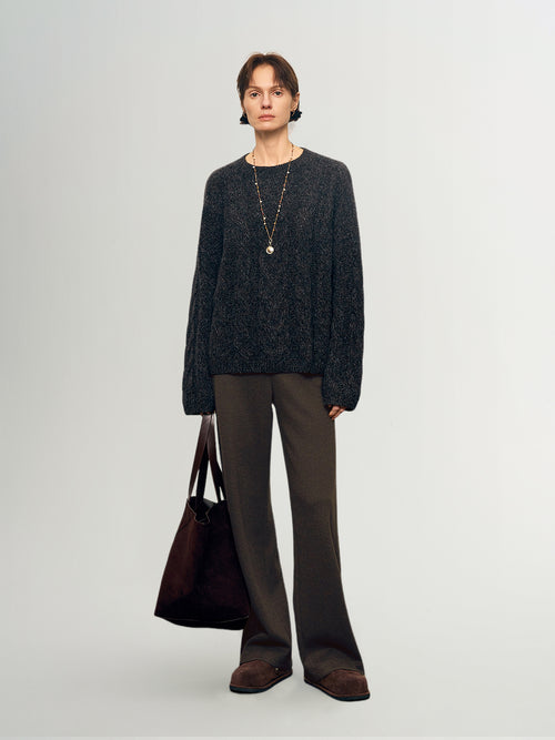 Load image 1 in gallery view. Person wearing a dark sweater and brown pants holding a bag on a light gray background