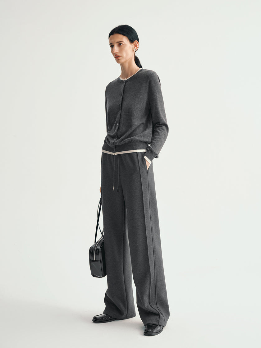 Person wearing a dark gray outfit with wide-leg pants and a black top on a white background