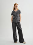 Woman wearing a gray t-shirt and wide-leg pants on a white background