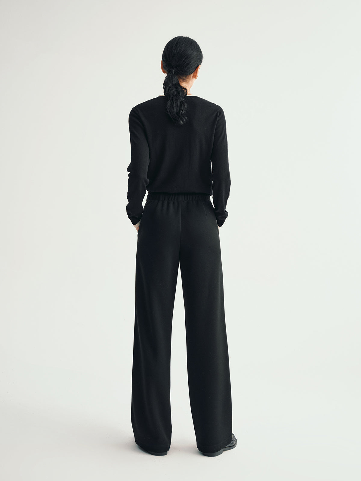 Person wearing a black outfit with wide-leg pants on a white background