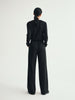 Person wearing a black outfit with wide-leg pants on a white background