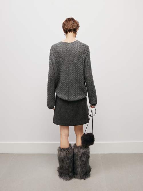 Load image 1 in gallery view. Women wearing a gray textured sweater and skirt with fur boots, holding a black bag.
