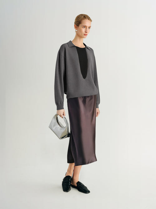 Load image 1 in gallery view. Woman wearing a gray blouse with a black top and satin skirt, holding a gray handbag on a white background.