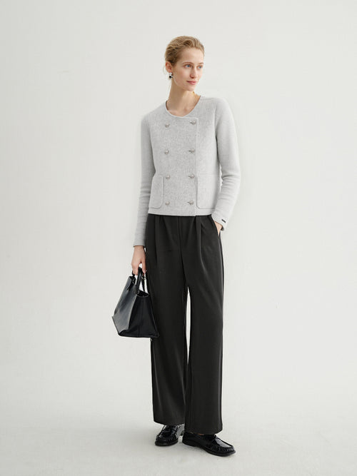 Load image 1 in gallery view. Woman wearing a gray cardigan, black pants, and holding a black handbag on a white background