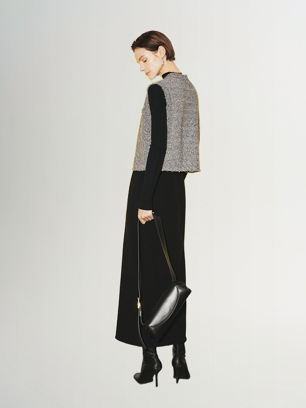 Woman wearing a stylish Tweed Knit Vest with a black dress and purse, showcasing a chic and modern look.