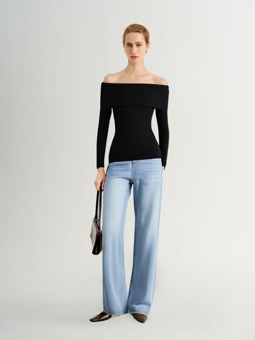 Load image 1 in gallery view. Woman wearing a black off-shoulder top and light blue jeans on a white background