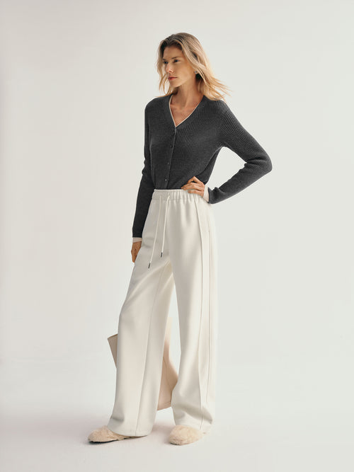 Load image 1 in gallery view. Woman wearing a dark gray cardigan and white pants on a light gray background