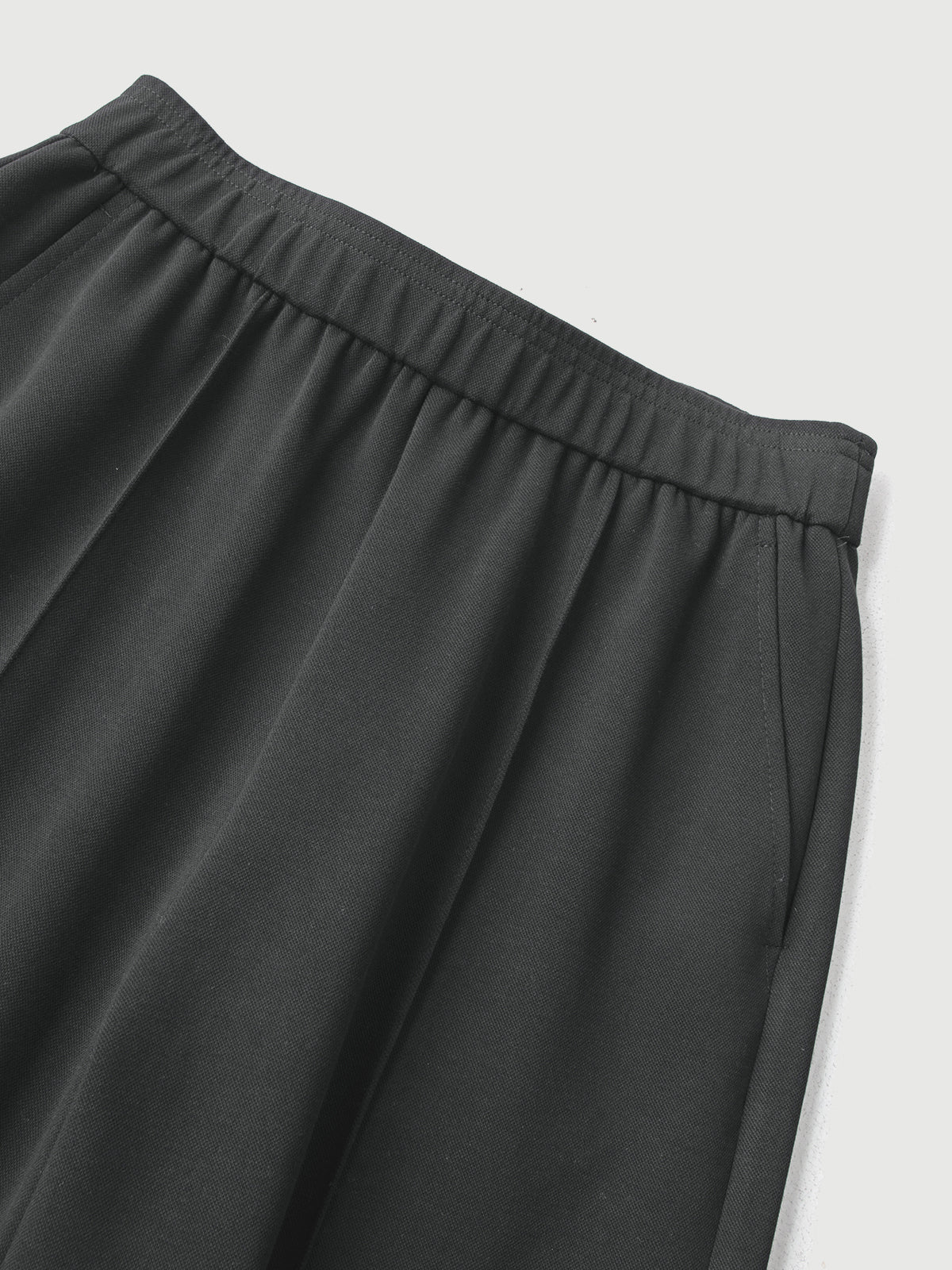 Close-up of dark gray pants on a light gray background