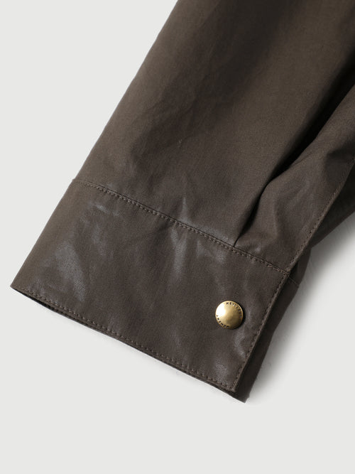 Load image 1 in gallery view. Close-up of a brown jacket sleeve with a gold button on a light gray background