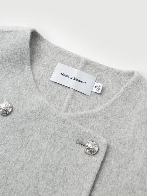 Load image 1 in gallery view. Gray garment with silver buttons and a visible brand label on a light gray background