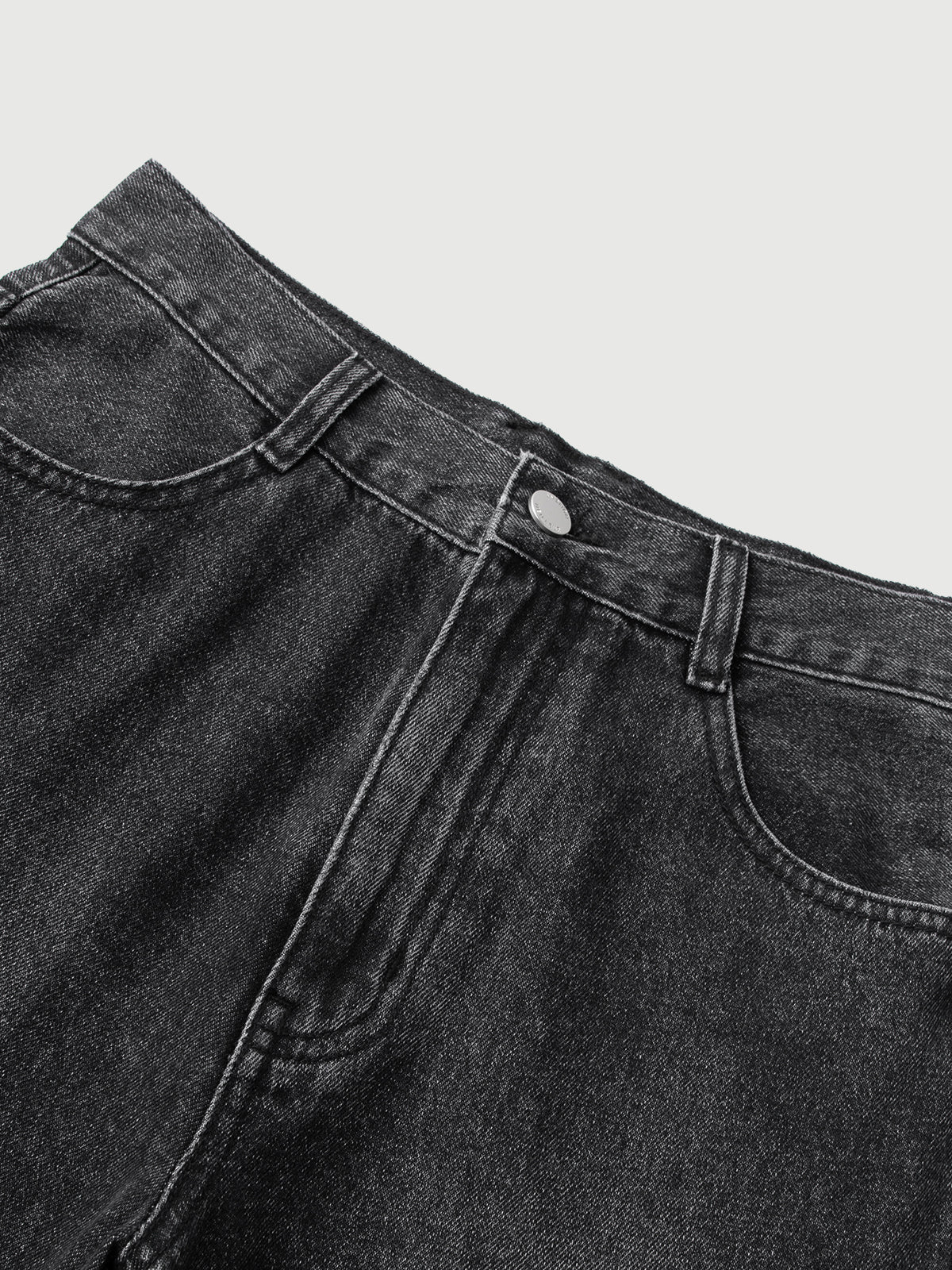 Close-up of black denim pants on a light gray background