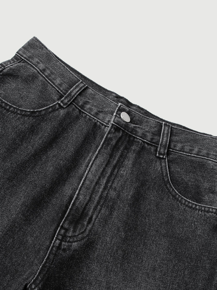 Close-up of black denim pants on a light gray background