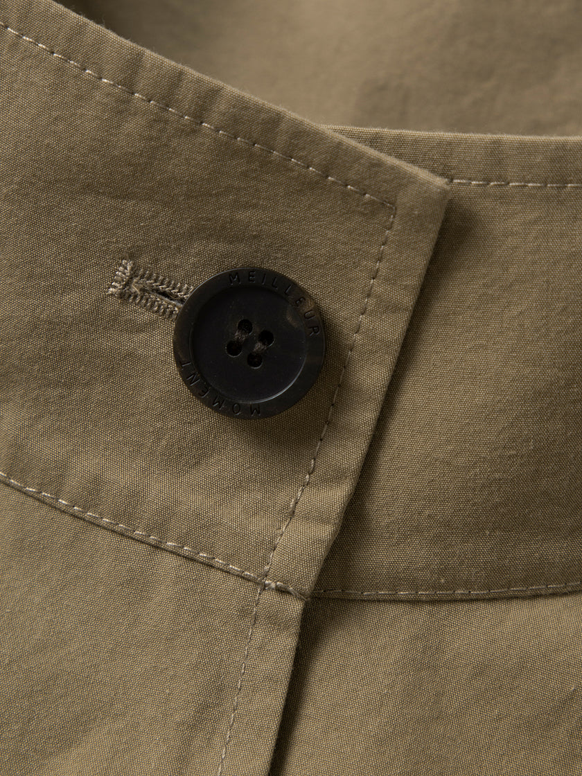 Close-up of a button on a beige fabric with a brand logo.