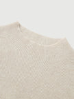 Close-up of a beige knit sweater on a light gray background