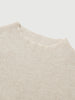 Close-up of a beige knit sweater on a light gray background