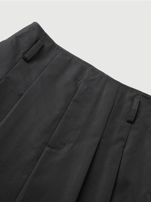 Load image 1 in gallery view. Close-up of dark gray pants with pleats on a light gray background