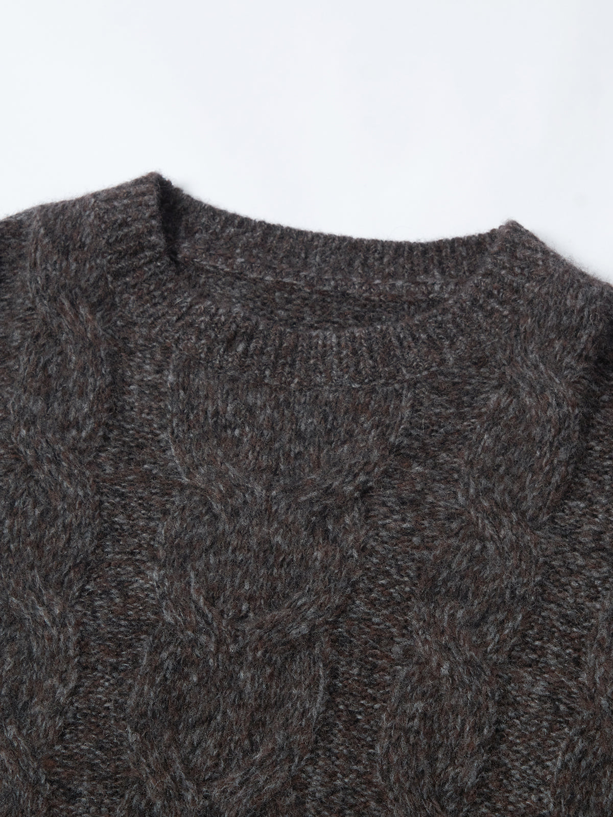 Close-up of a dark gray cable knit sweater on a white background
