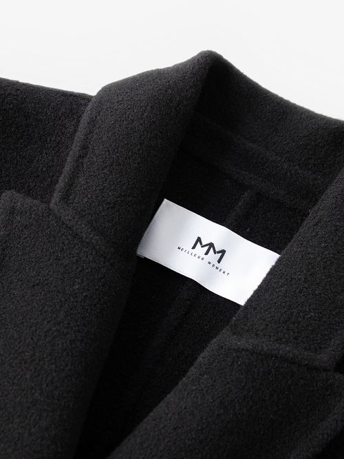 Load image 1 in gallery view. Black coat with a visible brand label on a white background