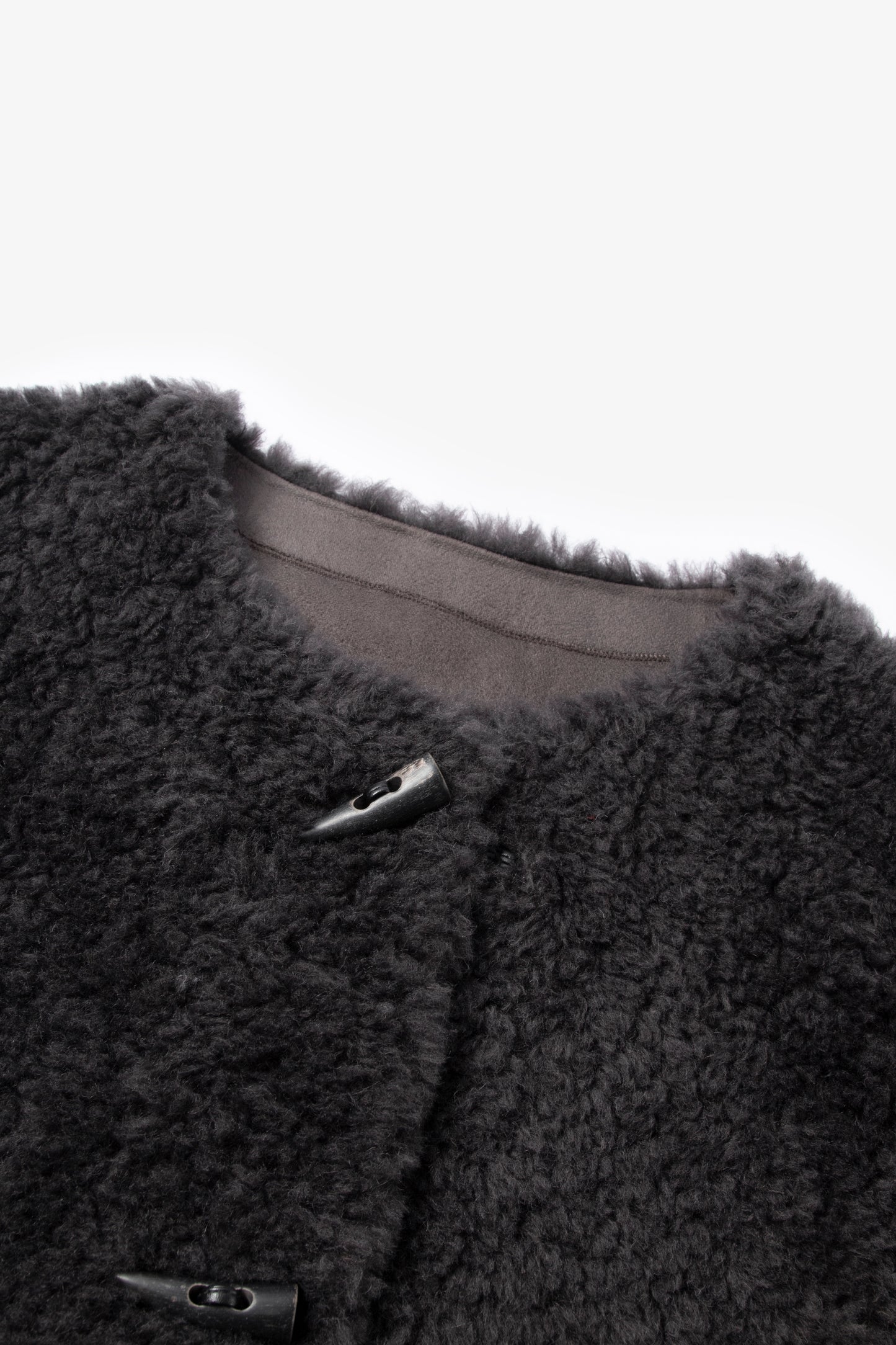 Close-up of a dark gray fleece jacket with buttons on a light gray background