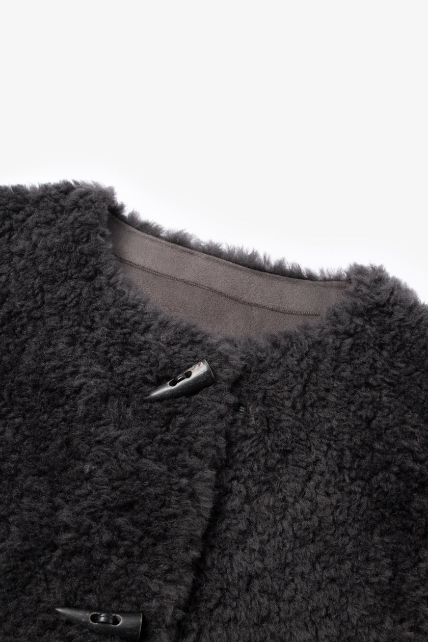 Close-up of a dark gray fleece jacket with buttons on a light gray background