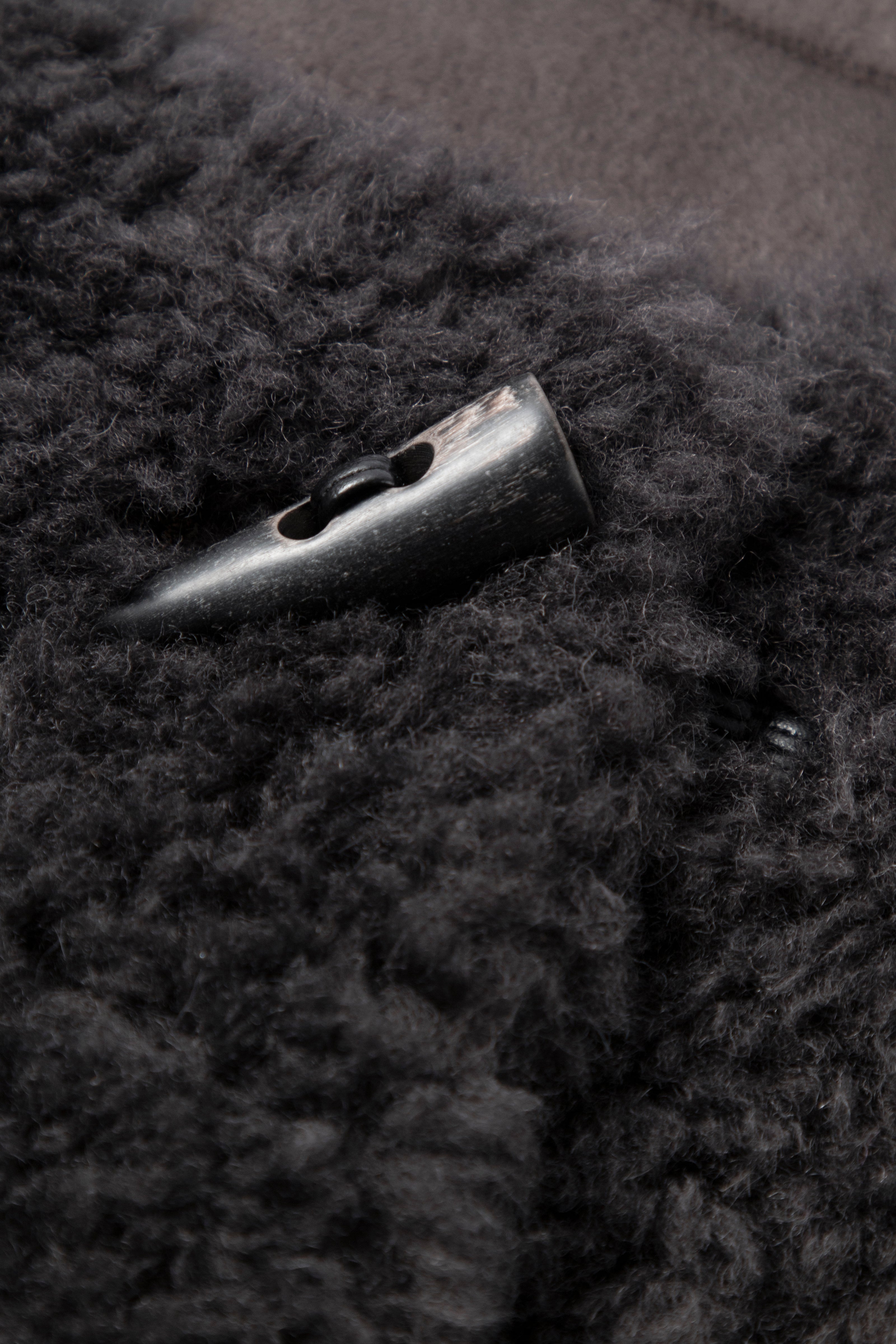Close-up of a button on a dark textured fabric