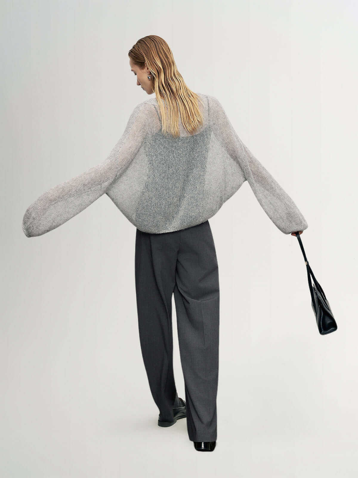 Cashmere-Silk Relaxed Pullover Sweater showcased on a model wearing gray trousers and carrying a black bag.