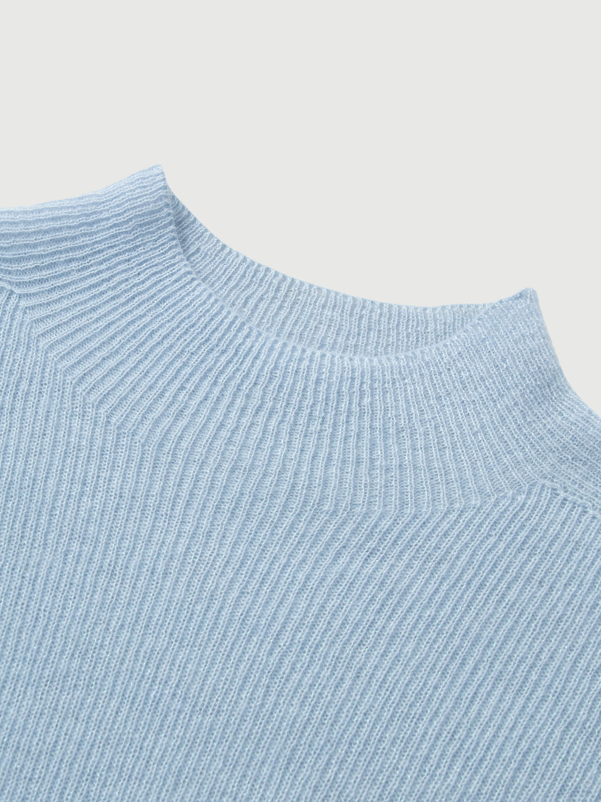 Close-up of a light blue ribbed sweater on a light gray background