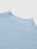 Close-up of a light blue ribbed sweater on a light gray background