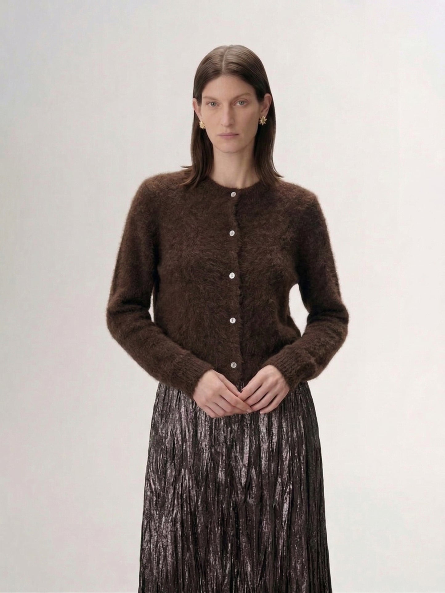 Silk-Cashmere Cardigan worn by a model, featuring a soft brown hue and button closure against a textured backdrop.