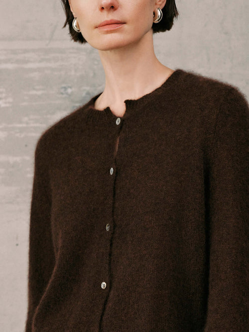 Load image 1 in gallery view. Silk-Cashmere Cardigan worn by a model, featuring a soft brown hue and button closure against a textured backdrop.