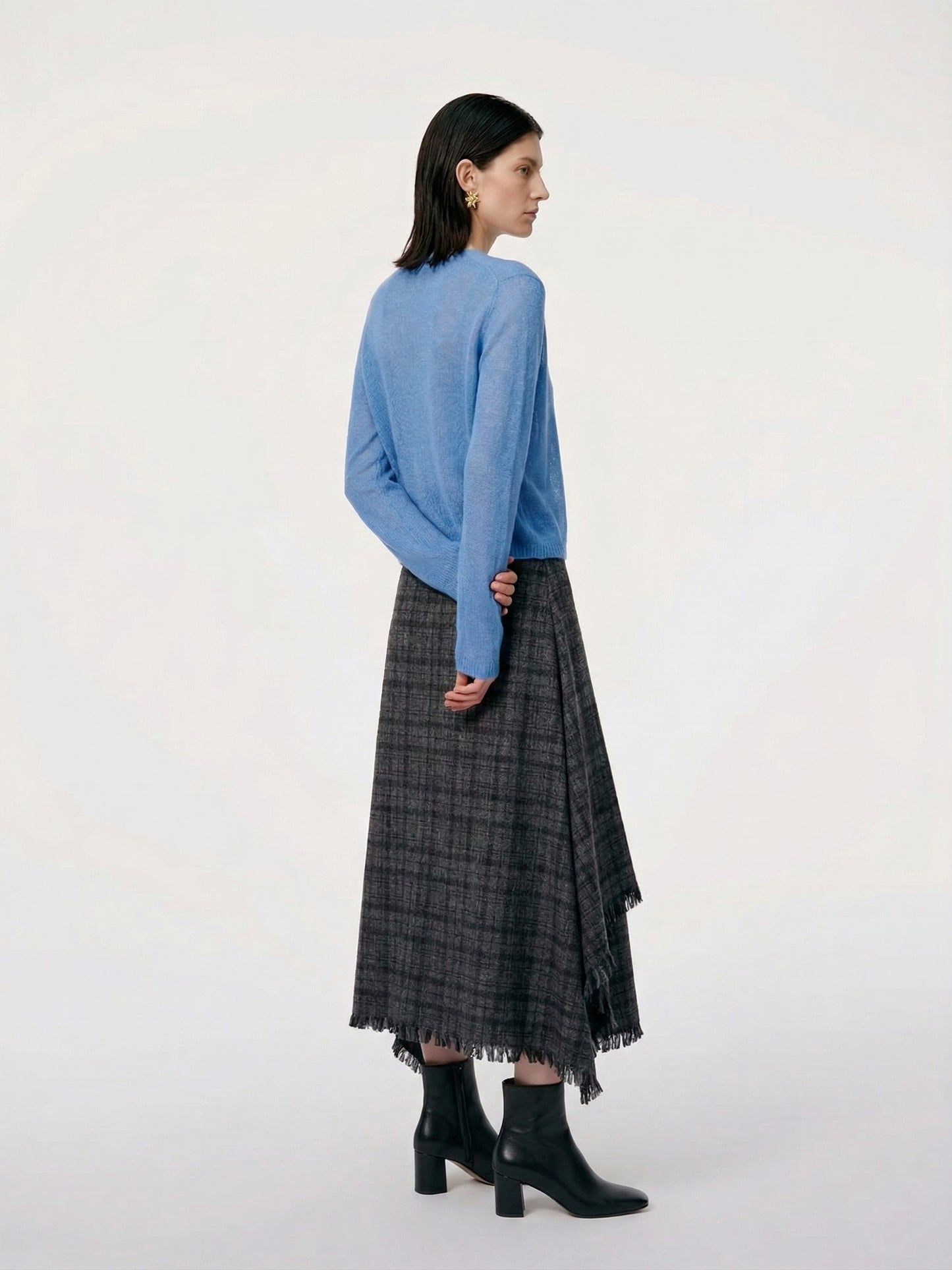 Model wearing a Silk-Cashmere Cardigan in soft blue, paired with a black plaid skirt and stylish accessories.