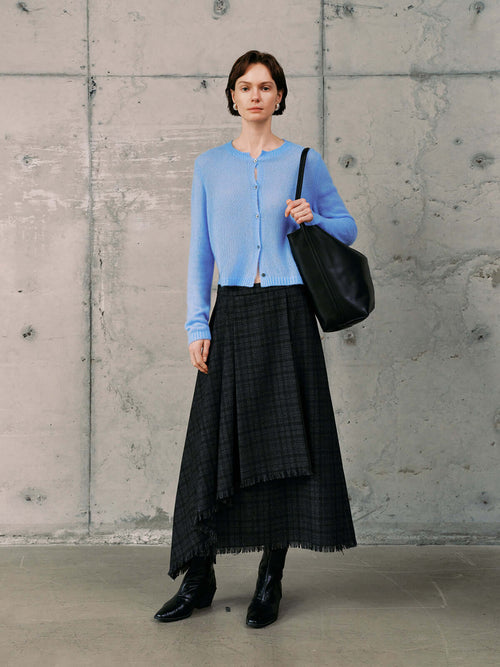 Load image 1 in gallery view. Model wearing a Silk-Cashmere Cardigan in soft blue, paired with a black plaid skirt and stylish accessories.