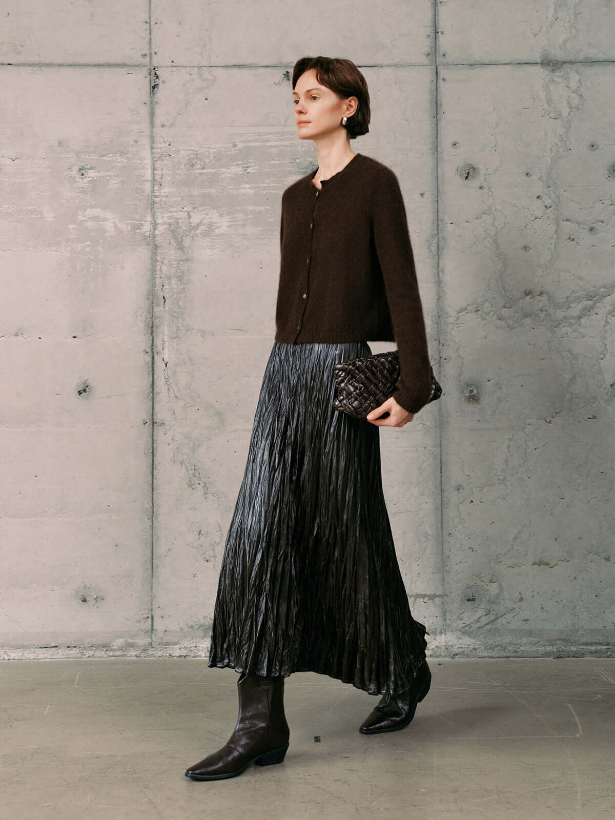 Silk-Cashmere Cardigan styled with a pleated metallic skirt and knee-high boots in a modern interior.