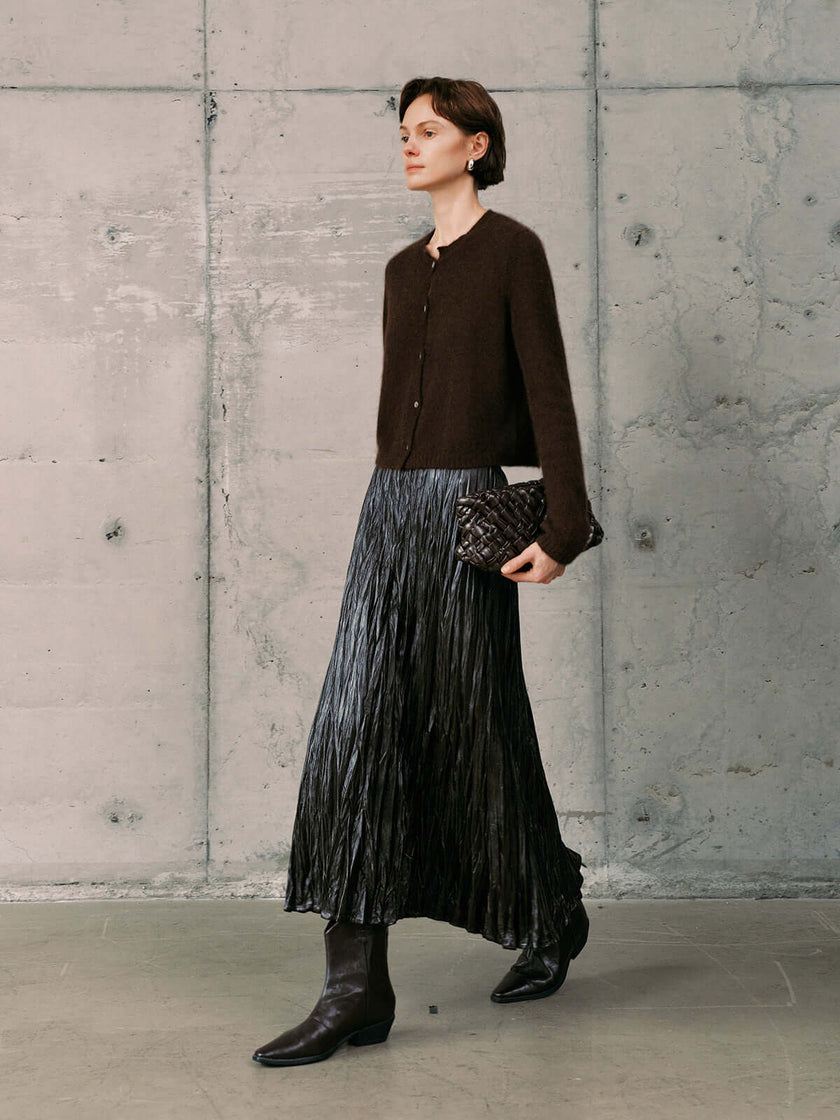 Silk-Cashmere Cardigan styled with a pleated metallic skirt and knee-high boots in a modern interior.