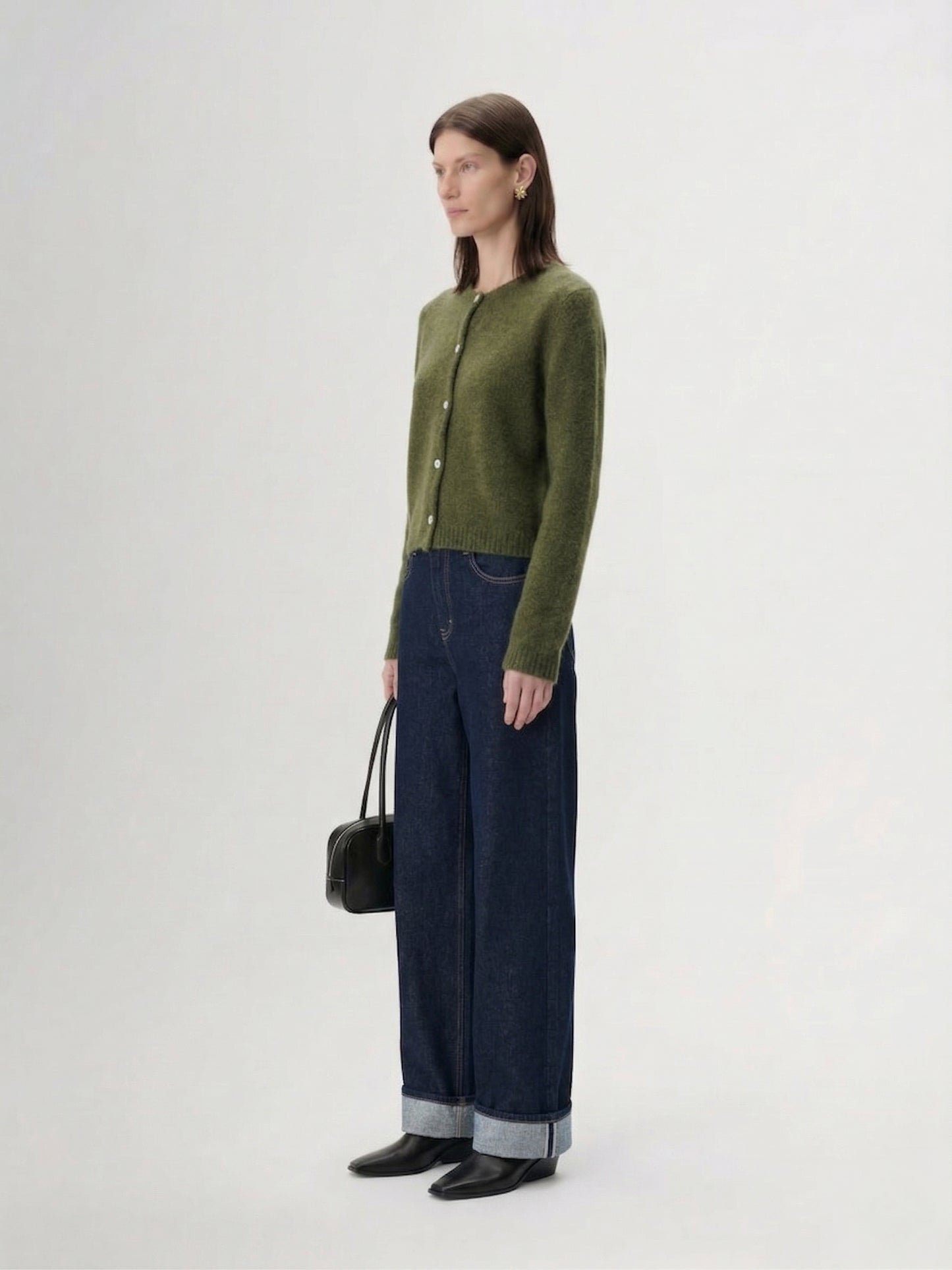 Silk-Cashmere Cardigan displayed over wide-leg trousers on a model against a minimalist concrete background.