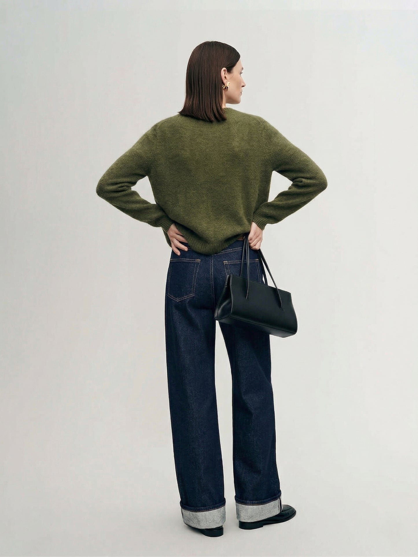 Silk-Cashmere Cardigan displayed over wide-leg trousers on a model against a minimalist concrete background.