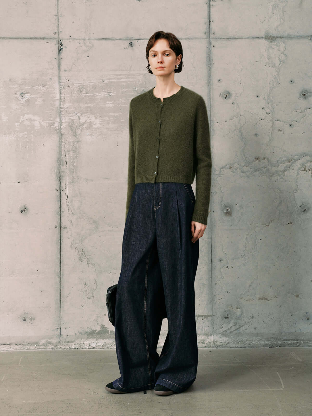 Silk-Cashmere Cardigan displayed over wide-leg trousers on a model against a minimalist concrete background.