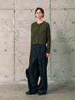 Silk-Cashmere Cardigan displayed over wide-leg trousers on a model against a minimalist concrete background.