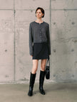 Silk-Cashmere Cardigan styled with a black skirt, boots, and a handbag against a textured concrete background.