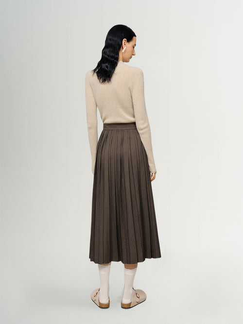 Load image 1 in gallery view. Woman wearing a beige sweater and brown pleated skirt on a white background