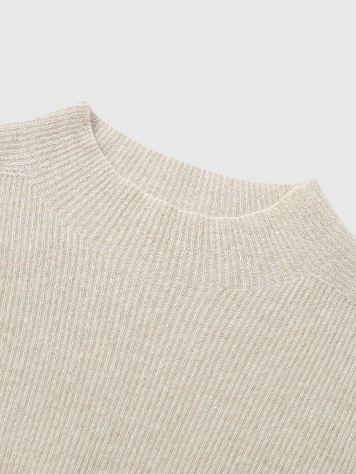 Close-up of a beige knit sweater on a light gray background