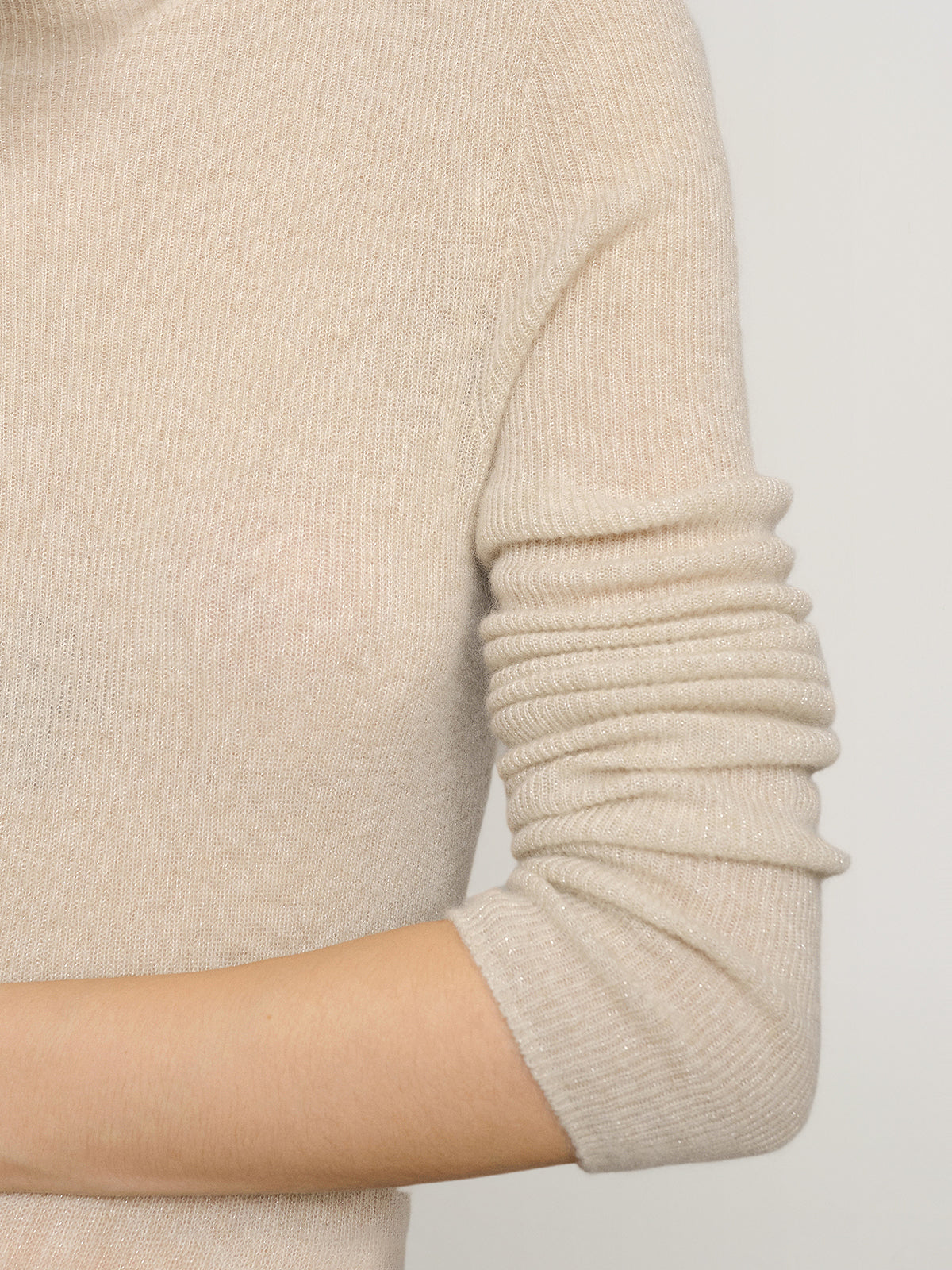Close-up of a beige sweater sleeve on a plain background