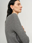 Woman wearing a gray sweater against a plain background